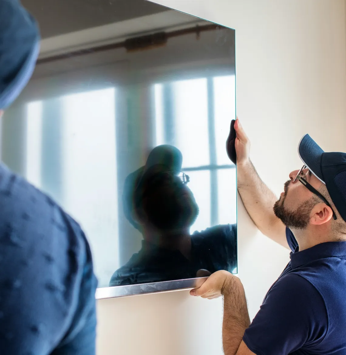 Dos personas montando un televisor de pantalla plana en la pared de una sala